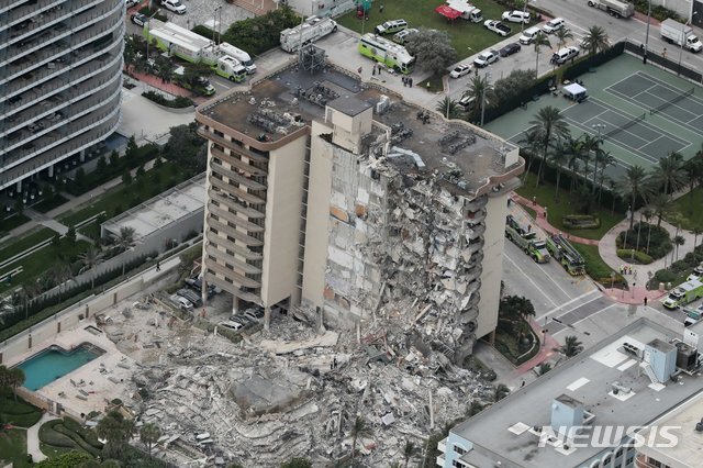 [서프사이드=AP/뉴시스]24일(현지시간) 미 플로리다주 마이애미데이드 카운티 서프사이드에서 12층짜리 챔플레인 타워 사우스 아파트가 무너져 잔해물이 무너진 벽면에 매달려 있다. 이날 새벽에 건물 일부가 무너져 아파트 136가구 중 55가구가 붕괴해 최소 1명이 숨지고 99명의 소재가 불분명해 사망자는 더 늘어날 것으로 우려된다.