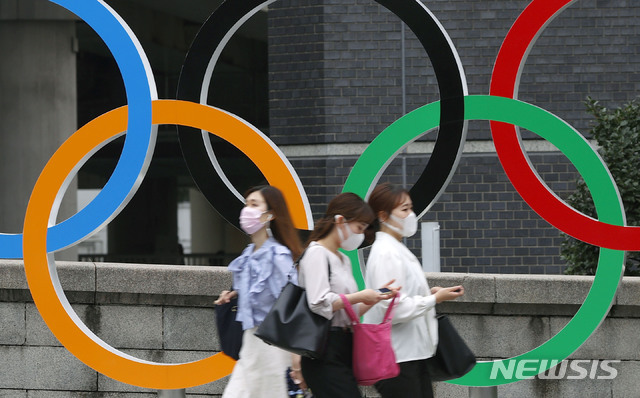 8일 일본 도쿄에서 코로나19 확산 방지를 위해 마스크를 쓴 사람들이  도쿄 올림픽 오륜 조형물 앞을 지나가고 있다. (출처: 뉴시스)