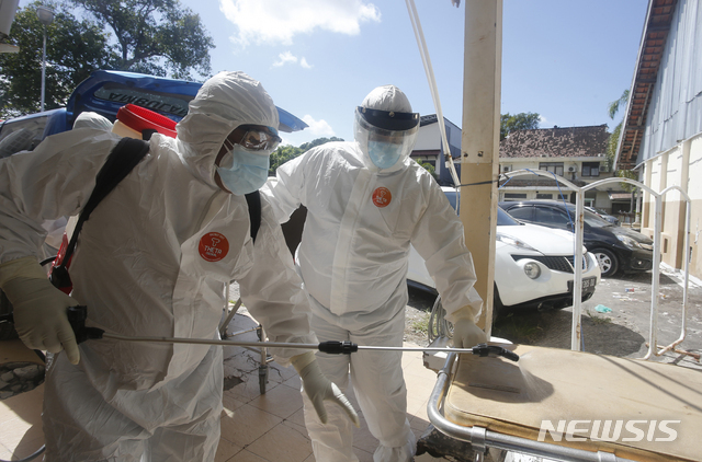[AP/뉴시스] 15일 인니 발리에서 의료 종사자들이 코로나19 사망자를 옮긴 뒤 소독하고 있다.