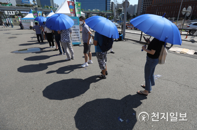 [천지일보=남승우 기자] 전국적으로 찜통더위가 이어지고 있는 16일 서울역 광장 임시 선별검사소에서 코로나19 검사를 기다리던 시민들이 검사소에 비치된 양산을 펼쳐 뜨거운 햇볕을 피하고 있다. ⓒ천지일보 2021.7.16