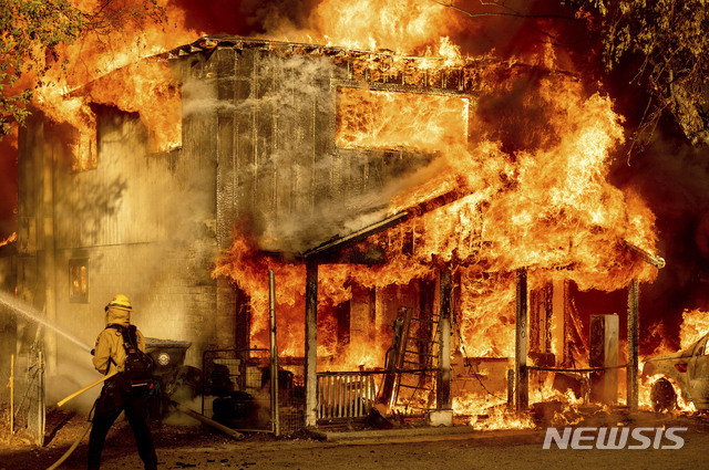지난 10일(현지시간) 미국 캘리포니아 도일의 인근 주택에 산불이 번지는 것을 막기 위해 한 소방관이 진압을 하고 있다. 폭염 속 강풍에 밀려 산불이 도일의 주택 여러채를 태웠다. (출처: 뉴시스)