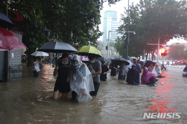 20일 중국 중부 허난성 성도 정저우에서 폭우가 내린 가운데 주민들이 침수된 길을 걷고 있다. (출처: 뉴시스)