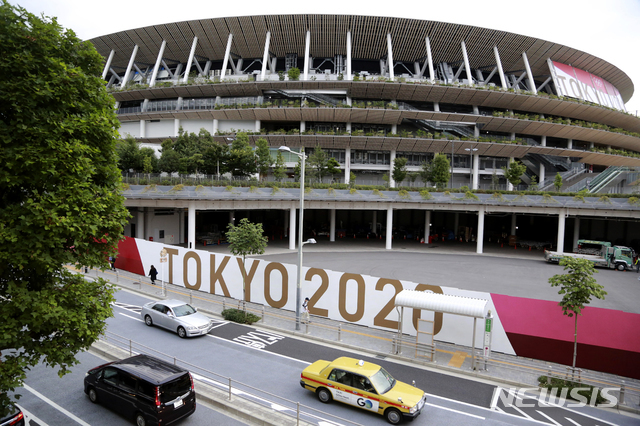 [도쿄=AP/뉴시스]지난달 29일 도쿄올림픽 경기가 열릴 일본 도쿄 국립경기장의 앞으로 차들이 지나가고 있다. 도쿄올림픽은 오는 23일 개막한다.
