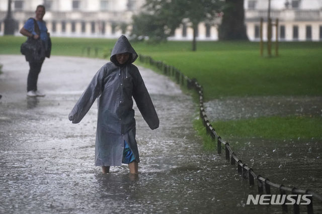 [런던=AP/뉴시스] 25일(현지시간) 영국 런던 세인트 제임스 공원에서 한 시민이 발목까지 차오른 물을 헤치며 비를 피하고 있다.