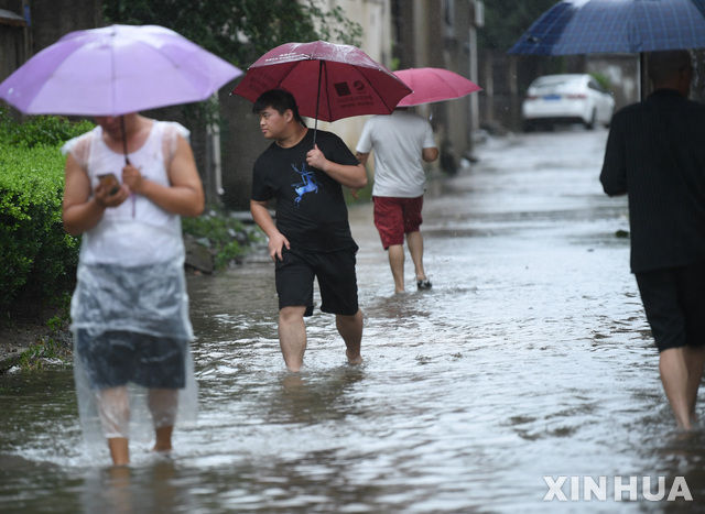 26일 중국 저장성 동부 닝보시에서 한 시민이 침수된 길을 걷고 있다. 태풍 인파는 이날 오전 9시 50분쯤 저장성에 두 번째로 상륙했다. (출처: 뉴시스)