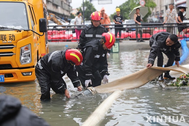 [저우산=신화/뉴시스] 25일 중국 저장성 저우산의 한 주택가에서 구조대원들이 빗물 제거 작업을 하고 있다.