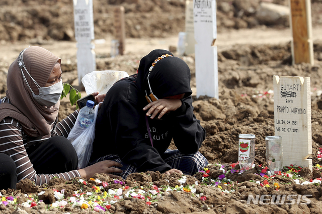 지난 7일(현지시간) 인도네시아 자카르타의 한 공동묘지에서 한 여성이 코로나19로 숨진 친지의 묘지 앞에 앉아 흐느끼고 있다. 지난 몇 주 동안 급증한 코로나19 사망자로 자카르타의 일일 매장량은 올 초보다 몇 배 늘어난 것으로 나타났다. (출처: 뉴시스)
