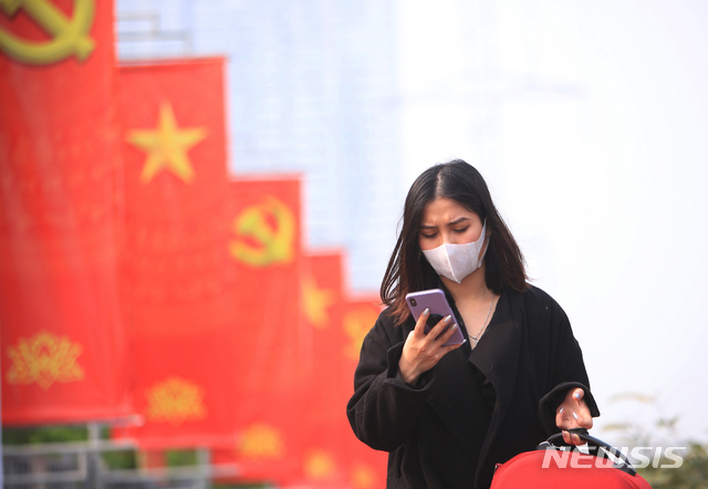 29일 베트남 하노이에서 마스크를 쓴 한 여성이 휴대전화를 보고 있다. 이날 베트남 당국은 인도와 영국에서 처음 발견된 코로나19 변이 바이러스가 혼합된 새 변이를 발견했다고 밝혔다. (출처: 뉴시스)