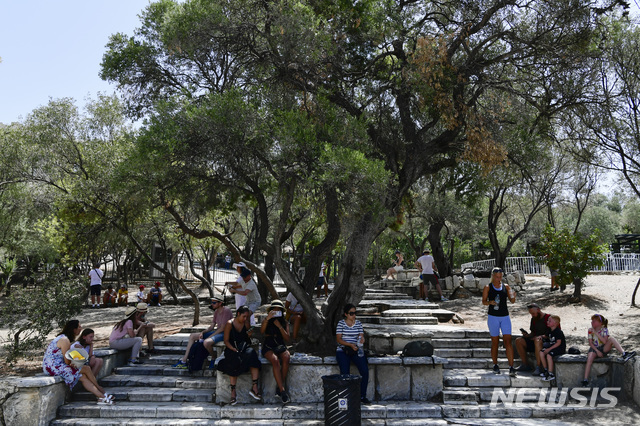 3일(현지시간) 그리스 아테네의 아크로폴리스 유적지 밖에서 관광객들이 나무 그늘에 앉아 쉬고 있다. 지중해 동부 지역을 뜨겁게 달군 폭염이 계속되면서 그리스 당국은 오후 시간대에 아크로폴리스 등 고대 유적지를 폐쇄했다. 아테네 등 일부 지역은 기온이 42도까지 올라가는 등 불볕더위가 이어지고 있다. (출처: AP/뉴시스)