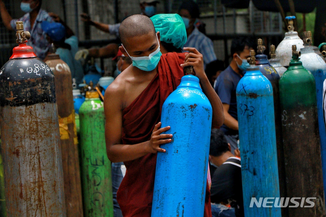 지난 7월 28일 미얀마 양곤 남다곤 공업지대의 나잉산소 공장에서 마스크를 쓴 승려가 산소를 충전하기 위해 산소 탱크를 들고 있다. (출처: 뉴시스)
