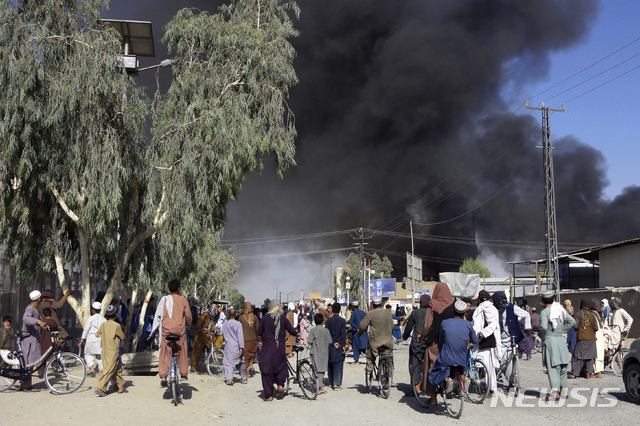 12일(현지시간) 아프가니스탄 남서부 칸다하르에서 탈레반과 아프간군 간의 교전으로 연기가 피어오르는 가운데 주민들이 이를 보고 있다. 아프간의 2, 3대 도시 칸다하르와 헤라트에 이어 북부 최대 도시 마자르-이-샤리프가 차례로 탈레반 손에 넘어가고, 잘랄라바드까지 점령을 당하면서 마지막 대도시 수도 카불은 완전히 포위된 상황이다. (출처: 뉴시스)