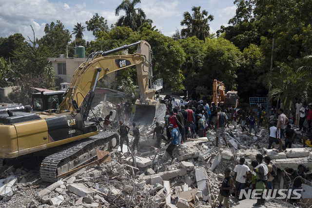 [레카이=AP/뉴시스] 16일(현지시간) 아이티 레카이에서 불도저 한 대가 지진으로 무너진 르망기에 호텔의 잔해를 치우고 있다.