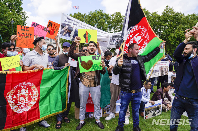 18일(현지시간) 영국 런던 의회 광장에서 아프가니스탄 관련 시위가 열려 시위대가 아프간 국기와 손팻말을 들고 있다. 영국 정부는 탈레반의 아프간 장악에 대응해 여성과 어린이 등 올해 아프간 난민 5천 명을 받아들일 계획이라고 밝혔다. (출처: 뉴시스)