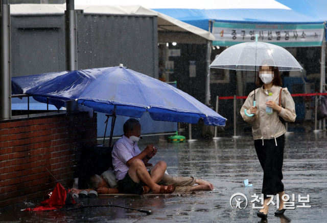 [천지일보=남승우 기자] 전국적으로 많은 비가 내릴 것으로 예보된 21일 오전 서울역 광장에서 노숙인들이 대형 파라솔을 펼치고 비를 피하고 있다. ⓒ천지일보 2021.8.21