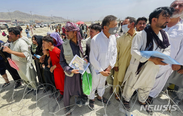 [카불=AP/뉴시스] 17일(현지시간) 수백 명의 사람이 아프가니스탄 카불 국제공항 밖에 모인 가운데 한 남성이 미국을 위해 일했음을 증명하는 증서를 들고 있다.
