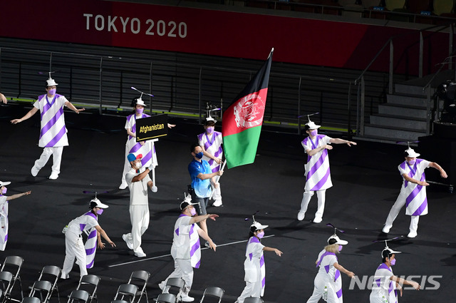 아프가니스탄 국기가 자원봉사자의 손에 들려 입장하고 있다. 이슬람 무장단체 탈레반이 정권을 재장악한 아프가니스탄은 결국 선수단을 파견하지 못했다. 하지만 개회식 선수단 행진에 아프간 국기가 합류하며 연대의 메시지를 전 세계에 전했다. (출처: 뉴시스)