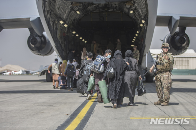 [카불=AP/뉴시스] 미 해병대 제공 사진으로 23일 탈레반 치하를 탈출하려는 아프간전 미군 협력자 가족들이 수도 카불의 하미드 카르자이 공항에서 미군의 경계 속에 수송기 C-17기에 오르고 있다. 2021. 8. 24.