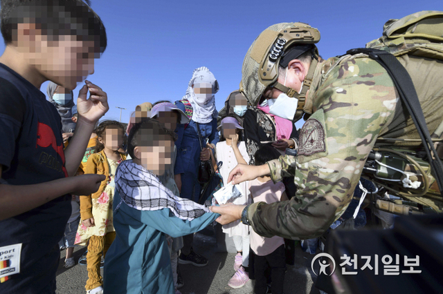 [천지일보=박준성 기자] 공군 최정예 특수부대 요원인 공정통제사가 25일(현지시간) 아프가니스탄 카불공항에서 한국으로 이송될 아프간인 현지 조력자의 자녀들에게 간식을 제공하고 있다. (제공: 공군) ⓒ천지일보 2021.8.26