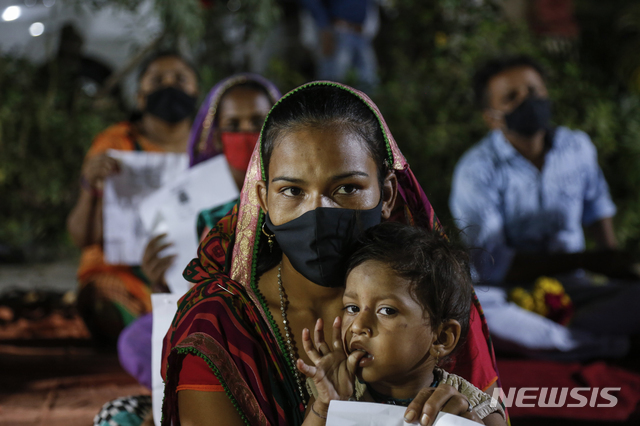 10일(현지시간) 인도 아마다바드에서 노숙자를 대상으로 코로나19 특별 백신 접종이 시행돼 한 노숙자 보호소에서 한 노숙인 여성이 아들과 함께 접종 순서를 기다리고 있다. (출처: 뉴시스)