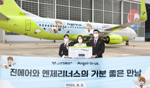 진에어 승무원들이 엔제리너스 브랜드를 래핑한 진에어 항공기를 배경으로 콜라보 기념 경품 프로모션용 스크래치 쿠폰을 안내하고 있다. (제공: 롯데GRS)