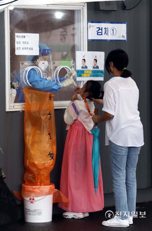 [천지일보=남승우 기자] 추석인 21일 오전 서울역 광장에 마련된 임시 선별검사소에서 한복을 입은 한 아이가 엄마와 함께 신종 코로나바이러스 감염증(코로나19) 검사를 받고 있다.방역당국에 따르면 이날 0시 기준 코로나19 신규 확진자는 1729명으로 집계됐다. ⓒ천지일보 2021.9.21