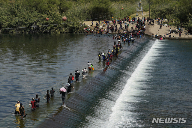 멕시코서 미국 넘어가는 아이티 이주민들[델리오=AP/뉴시스] 18일(현지시간) 미 텍사스주 델리오에서 아이티 이주민들이 댐을 건너 미국으로 넘어가고 있다. 이들은 이 댐을 목욕과 빨래뿐 아니라 멕시코에서 미국으로 건너가기 위한 주요 통로로 이용하고 있다. 텍사스주 정부는 아이티 불법 이민자들을 되돌려보내기 위한 노력을 가속화하고 국경을 폐쇄하는 등 자국민을 보호하는 데 최선을 다할 것이라고 밝혔다.