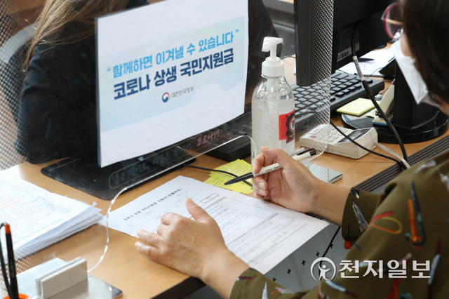 [천지일보=남승우 기자] 전 국민의 약 88%가 1인당 25만원씩 받는 코로나 상생 국민지원금 신청 접수가 시작된 6일 오후 서울 서초구 서초1동 주민센터에서 한 시민이 국민지원금 신청 관련 안내를 받고 있다. 시행 첫 주에는 지급 대상 여부 조회, 온·오프라인 신청 모두 출생연도 끝자리 기준 요일제를 적용한다. 온라인 신청은 6일부터, 오프라인 신청은 오는 13일부터다. 지원금은 10월29일까지 신청할 수 있고 12월31일까지 사용해야 한다. ⓒ천지일보 2021.9.6