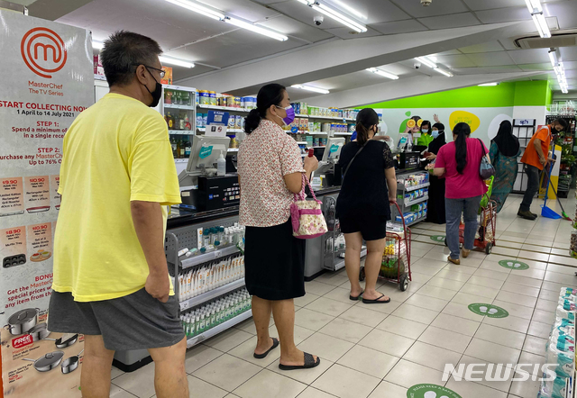 [싱가포르=AP/뉴시스]14일(현지시간) 싱가포르의 한 슈퍼마켓에서 코로나19 확산 방지를 위해 마스크를 쓴 사람들이 사회적 거리를 두고 계산을 하기 위해 줄 서 있다.