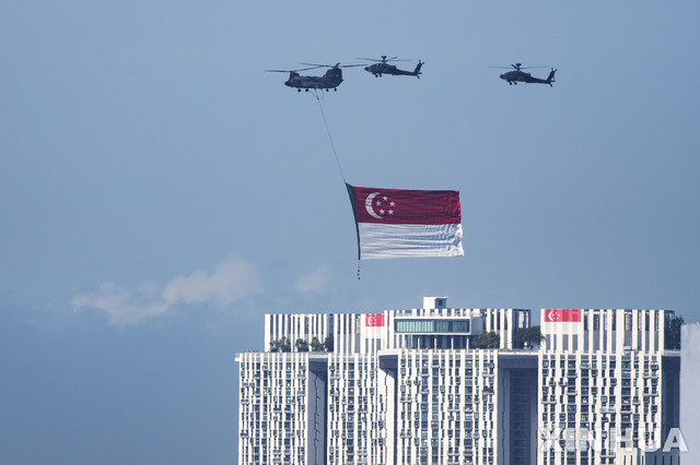 [싱가포르=신화/뉴시스] 싱가포르 독립 제56주년인 9일 헬리콥터들이 싱가포르 국기를 매달고 축하 비행을 하고 있다. 싱가포르는 독립기념일인 9일까지 전체 인구의 3분의 2 이상 완전 접종 목표를 달성한 것으로 나타났다. 이에 따라 싱가포르는 10일부터 코로나19 봉쇄를 해제한다. 2021.08.09.