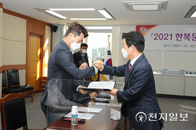 18일 진주시청에서 열린 ‘2021 진주실크 한복’ 보고회에서 조규일 시장이 BTS 한복정장 디자이너로 알려진 김리을 디자이너에게 진주실크 홍보대사 위촉장을 전달하고 있다. (제공: 진주시) ⓒ천지일보 2021.10.18