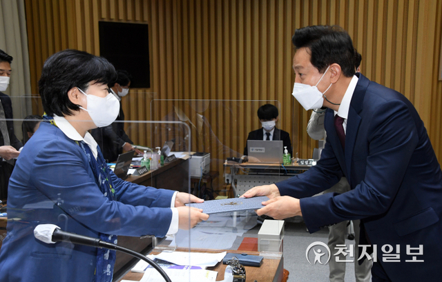 증인선서 후 서영교 위원장에게 증인선서문을 전달하는 오세훈 서울시장. (제공: 서울시장) ⓒ천지일보 2021.10.19