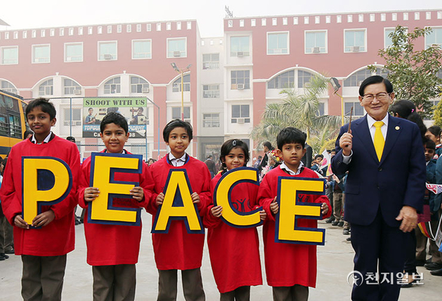 2015년 12월 20일 인도 라마갸학교에서 학생들이 IWPG(국제청년평화그룹)가 새겨진 빨간 티셔츠를 입고 ‘PEACE’가 적힌 손피켓을 들고 이 대표를 맞은 후 기념 사진을 촬영하고 있다. (제공: HWPL) ⓒ천지일보 2021.10.25