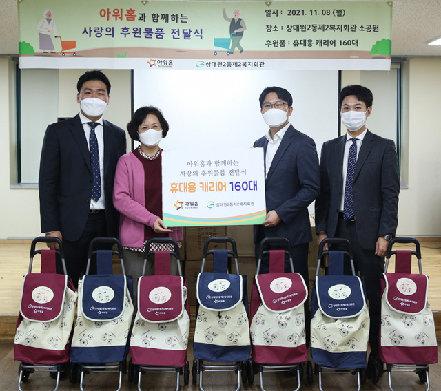 아워홈이 지난 8일 상대원2동 제2복지회관에서 ‘이동식 장바구니’ 후원 행사를 개최해 참석자들이 기념사진을 촬영하고 있다. (제공: 아워홈)