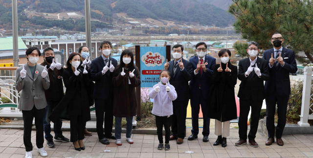 정태영 세이브더칠드런 사무총장(우측 네 번째), 민명기 롯데제과 대표이사(우측 다섯 번째), 김영록 원통초 교장(좌측 다섯 번째) 등 총 60여명이 참석한 개관식에서 기념사진을 촬영하고 있다. (제공: 롯데제과)