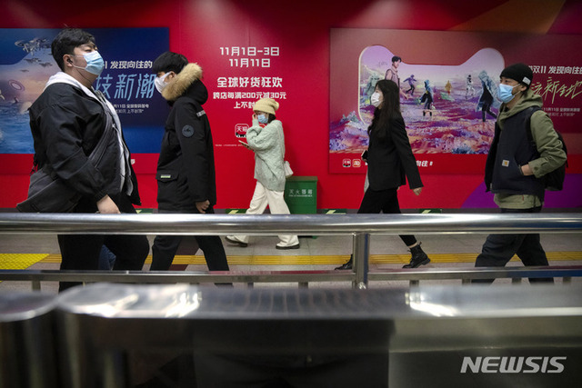 [베이징=AP/뉴시스] 중국 독신자의 날(광군제)인 11일 베이징의 한 지하철역에서 마스크를 쓴 시민들이 중국의 전자상거래업체 알리바바가 소유한 온라인 쇼핑 플랫폼 '티몰'의 광고판 앞을 지나가고 있다. 중국 최대의 쇼핑 축제인 광군제가 정부의 규제 강화로 올해는 조용한 분위기를 보이는 것으로 알려졌다. 2021.11.11.