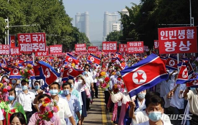[평양=AP/뉴시스] 9일 북한 평양의 개선문 앞에서 평양 시민들이 정권 수립 73주년(9·9절)을 기념해 구호가 적힌 손팻말을 들고 행진하고 있다. 2021.09.10.