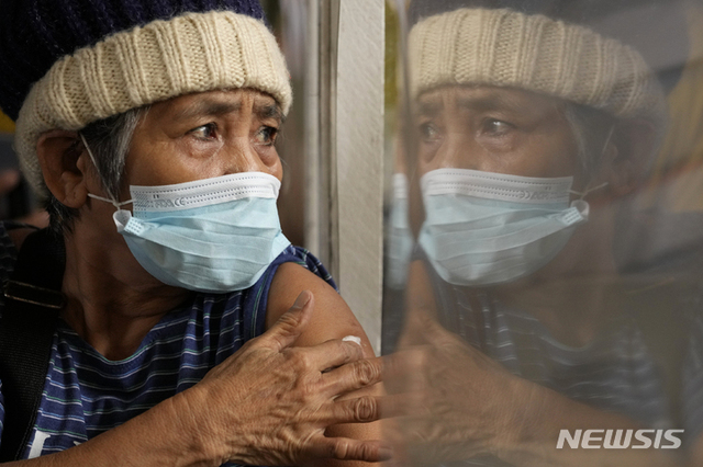 11월 29일(현지시간) 필리핀 케손시의 한 학교에서 한 여성이 아스트라제네카의 코로나19 백신을 접종받은 후 팔을 문지르고 있다. (출처: 뉴시스)