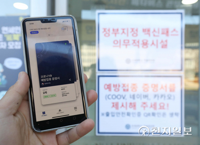 [천지일보=남승우 기자] 식당·카페 등 다중이용시설 16곳에 적용 중인 방역패스(접종증명·음성확인제) 시행이 의무화된 13일 오후 서울 서대문구 연세대학교 중앙도서관 입구에서 한 시민이 코로나19 예방접종 증명서를 들어 보이고 있다. ⓒ천지일보 2021.12.13