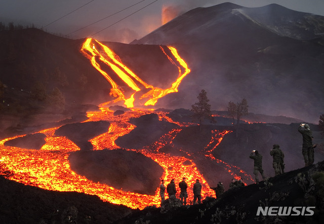 11월 29일 스페인 카나리아 제도 라 팔마섬에서 화산이 계속 폭발하며 용암이 흐르는 가운데 육군 장병들이 언덕 위에서 이를 보고 있다. (출처: 뉴시스)