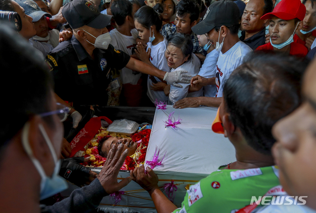 2월 24일 미얀마 양곤에서 장례식이 열린 가운데 틴 틴 윈(가운데)이 그의 아들인 틴 헤인의 시신을 보며 눈물을 흘리고 있다. 틴 헤인은 나흘 전 군부가 교도소에서 범죄자를 풀어 공포를 조성하고 폭력을 행사한다는 우려로 설립된 이웃감시단체의 자원봉사자로 일하던 중 총에 맞아 숨졌다.  (출처: 뉴시스)