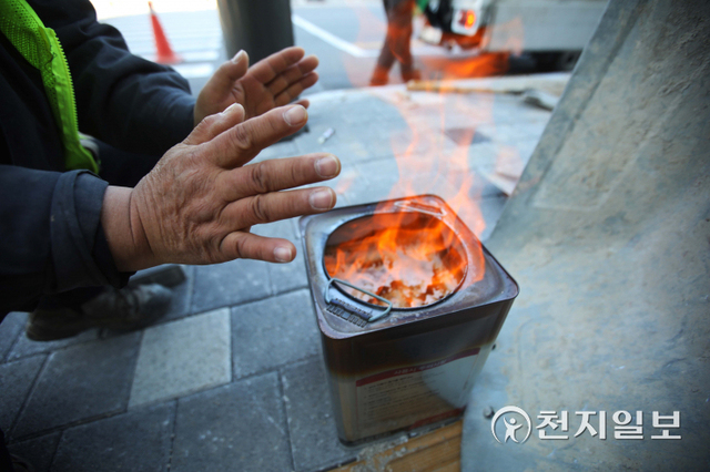 [천지일보=남승우 기자] 올 겨울 들어 서울에 처음으로 한파주의보가 내려진 17일 서울 시내의 한 거리에서 보도블럭 교체 공사를 하던 작업자가 모닥불에 손을 녹이고 있다. ⓒ천지일보 2021.12.17