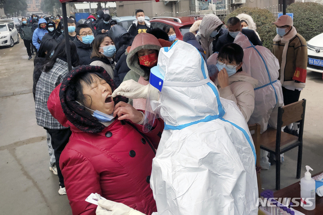 [안양=AP/뉴시스] 10일(현지시간) 중국 허난성 안양시의 화현에서 한 의료인이 주민들을 대상으로 코로나19 검사를 하고 있다. 베이징 올림픽 개최를 앞두고 베이징과 인접한 안양에서 코로나19 사례가 급증하자 중국 정부는 인구 500만의 안양시를 봉쇄했다.