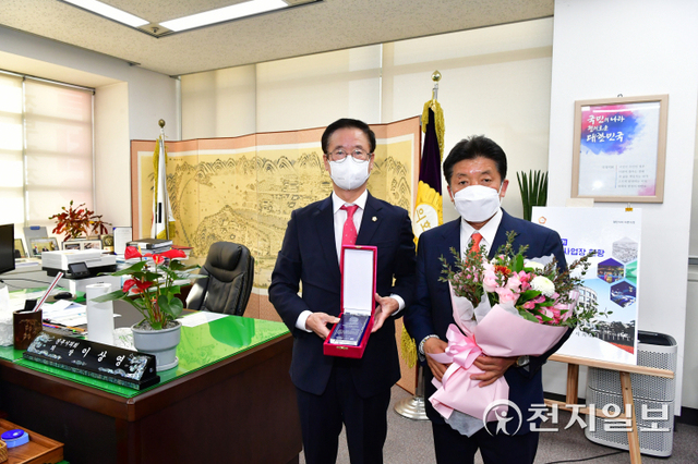 이상영 진주시의회 의장(왼쪽)이 백승흥 의원에게 경남시군의회 의장협의회 ‘지방의정 봉사대상’을 대신 전달하고 있다. (제공: 진주시의회) ⓒ천지일보 2022.1.17