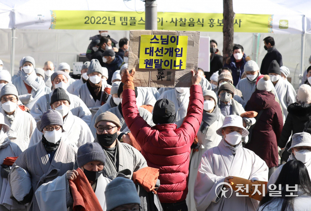 [천지일보=남승우 기자] 21일 오후 서울 종로구 조계사 앞에서 ‘종교편향·불교왜곡 근절과 한국불교 자주권 수호를 위한 전국승려대회’에 참석하기 위해 이동하는 스님들 사이로 한 시민이 승려대회를 규탄하는 내용이 담긴 피켓을 들고 있다. ⓒ천지일보 2022.1.21