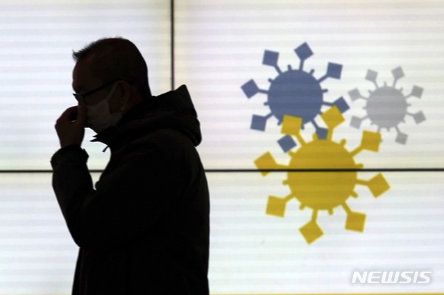 지난 13일 일본 도쿄에서 코로나19 오미크론 변이에 대한 캠페인 전광판 앞에서 한 시민이 걷고 있다. (출처: 뉴시스)