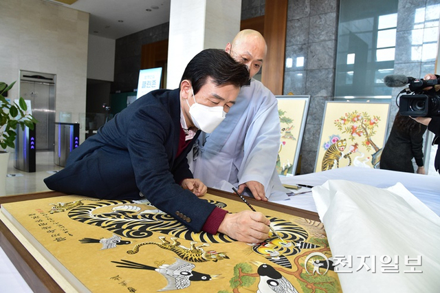 조규일 진주시장이 지난해 12월 4일 민화작품에 눈동자를 그리는 점안식에 참여해 민화 ‘진주호랑이(곽경희 작가)’를 완성하고 있다. (제공: 진주시) ⓒ천지일보 2022.1.2