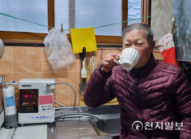 [천지일보 신안=김미정 기자] 허영호씨가 한우물 정수기에서 받은 물을 마시고 있다. ⓒ천지일보 2022.2.15