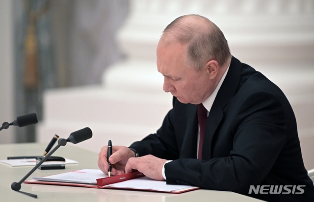 [모스크바=AP/뉴시스] 블라디미르 푸틴 러시아 대통령이 21일(현지시간) 모스크바 크렘린궁에서 우크라이나 동부 분쟁 지역인 돈바스 지역(도네츠크, 루한스크)의 독립을 인정하는 문서에 서명하고 있다. 푸틴 대통령은  이들 지역에 러시아 군대를 파견해 러시아 정부가 '평화유지 활동'을 수행할 것이라고 밝혔다.