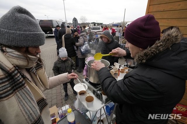 25일(현지시간) 우크라이나 피난민들이 접경 도시인 폴란드 남동부 메디카에 도착해 따뜻한 음료를 제공받고 있다. 유엔 관계자들은 우크라이나 국민 약 10만명이 피난길에 오른 것으로 보이며 전투가 확대될 경우 피난민은 400만명 정도로 늘어날 것이라고 내다봤다. (출처: 뉴시스)