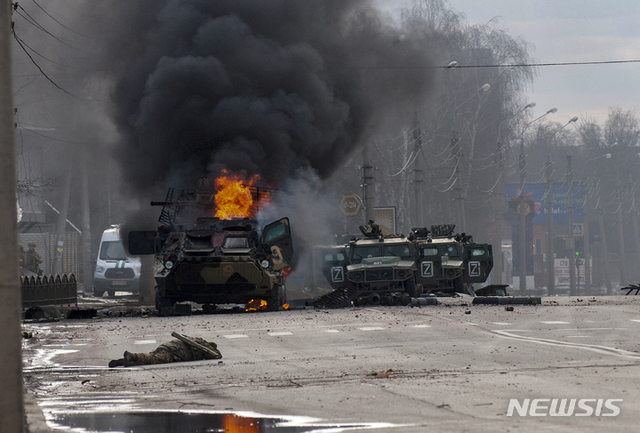 [하르키우=AP/뉴시스] 지난 27일(현지시간) 우크라이나 하르키우에서 러시아군 병력수송 장갑차(왼쪽)가 불타고 있고 그 앞에 생사를 알 수 없는 한 군인이 쓰러져 있다. 2022.02.28.